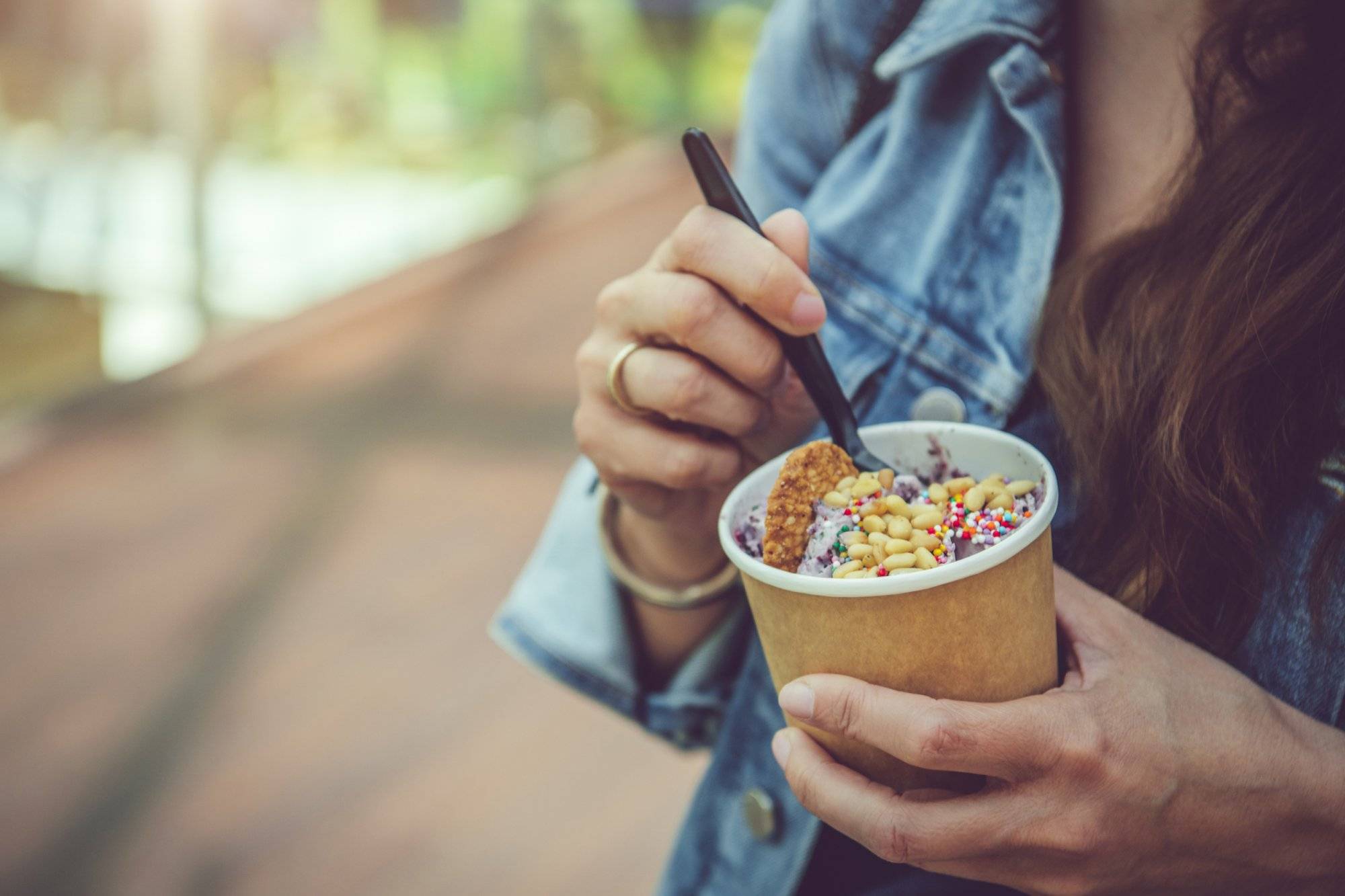 Young woman eating healthy rolled ice-cream or yogurt with fruits or berries, cookies, candy and mint Young woman eating healthy rolled ice-cream or yogurt with fruits or berries, cookies, candy and mint
