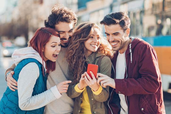 Group of young people watching at a smart phone and laughing