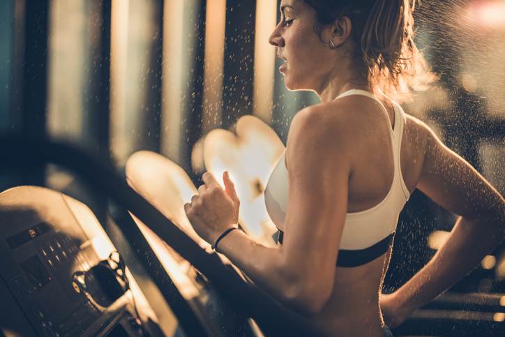 Sweaty woman running on treadmill during sports training in a gym. Sweaty woman running on treadmill during sports training in a gym.