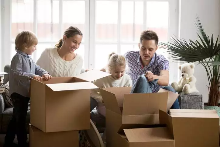 Young happy family with children packing boxes on moving day